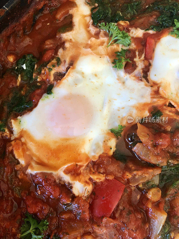 全框地中海健康早餐shakshouka / shakshuka / chakchouka在平底锅，鸡蛋煮在番茄酱，辣椒，洋葱，橄榄油和大蒜